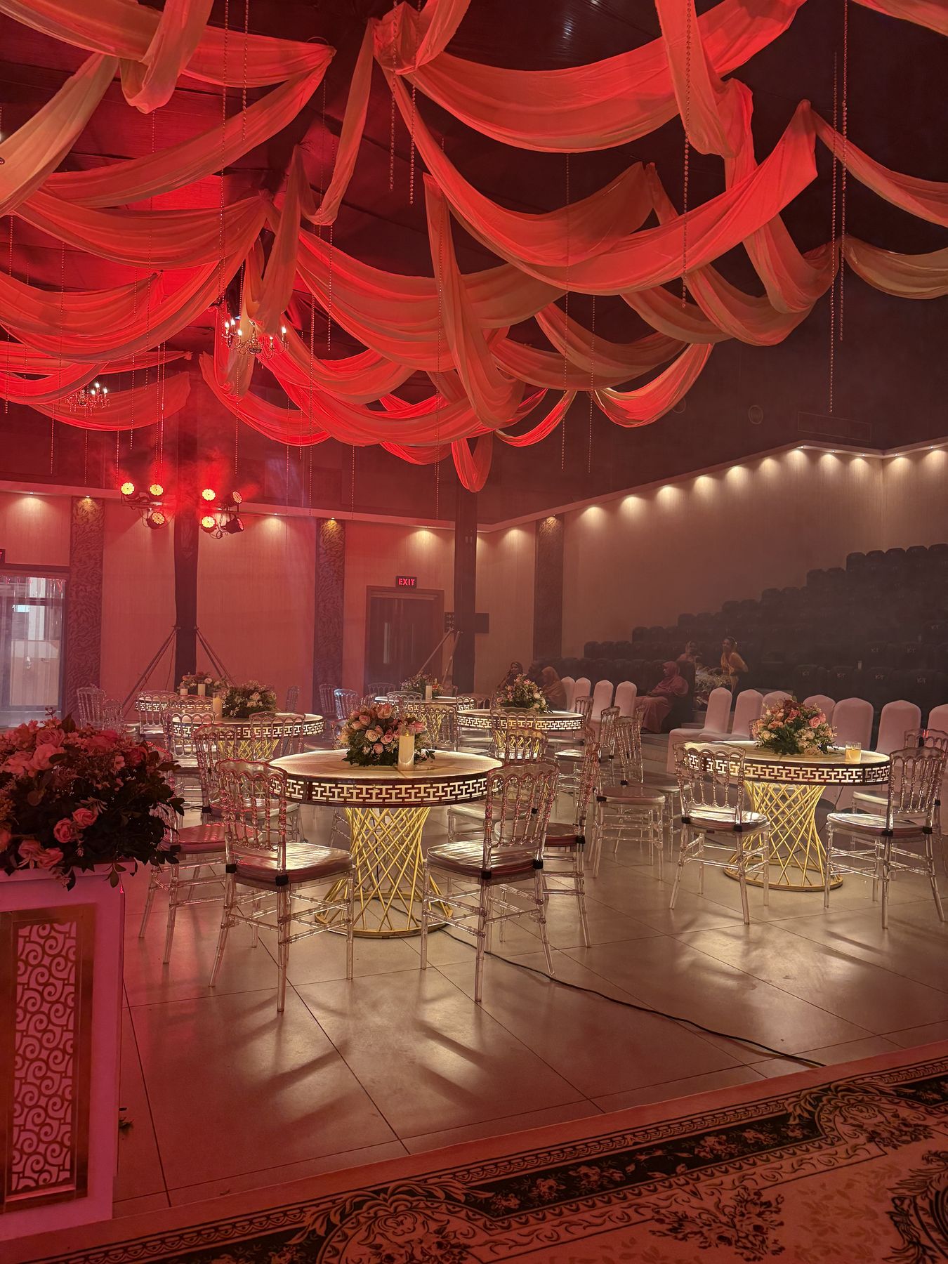 Banquet hall with red-lit draped ceiling and gold tables