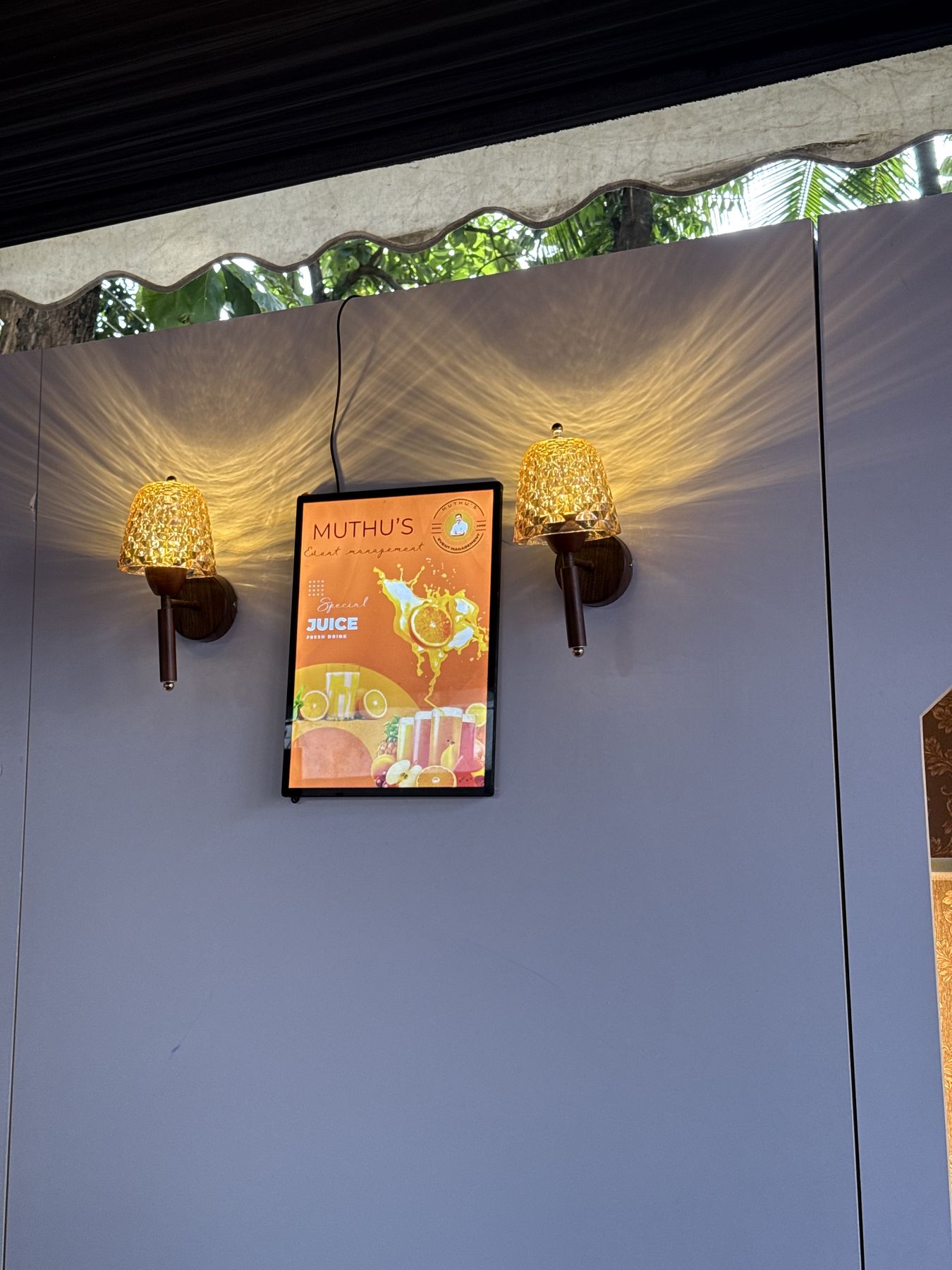 Muthu's juice bar menu screen between crystal wall lamps