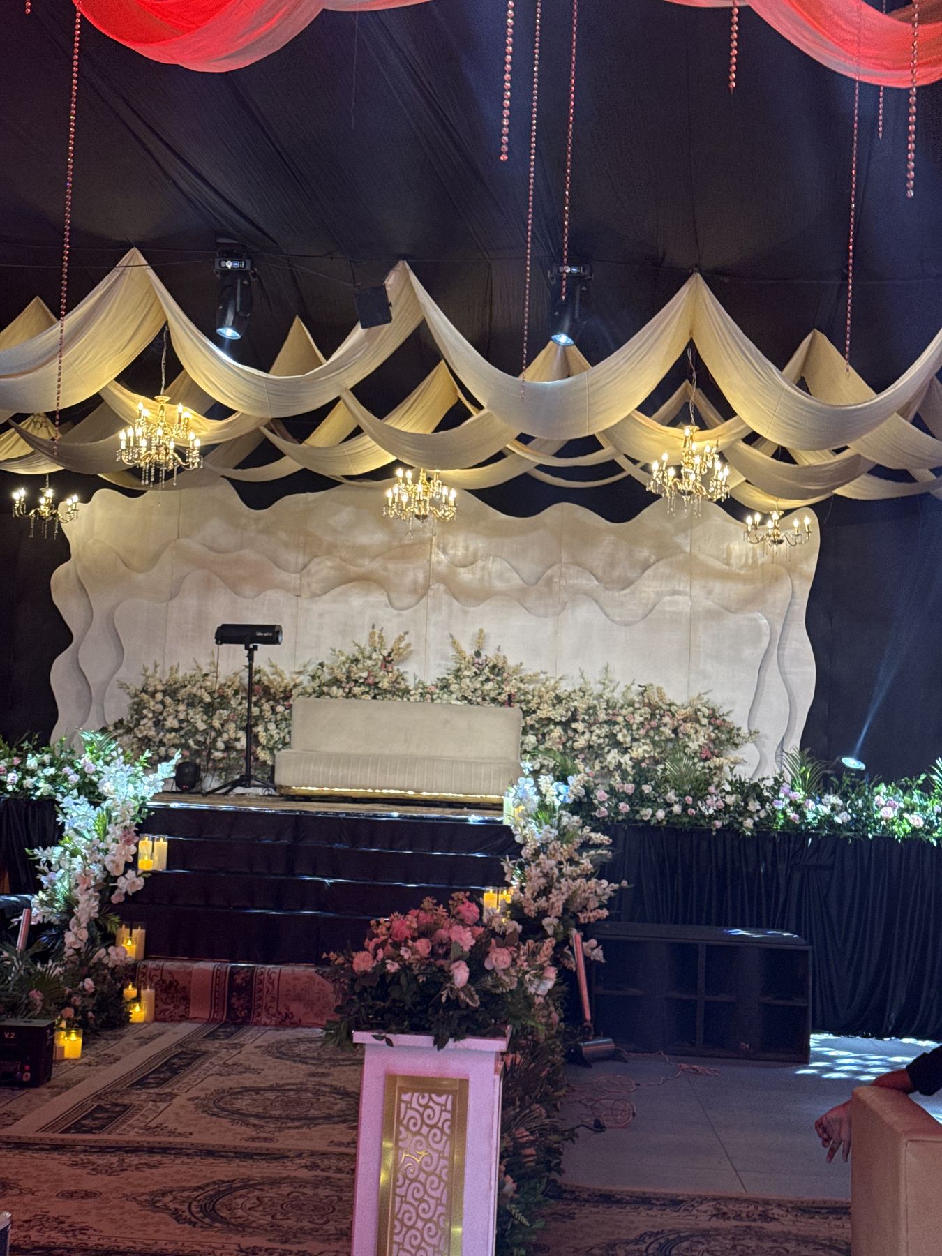Wedding stage with draped ceiling, chandeliers and white florals